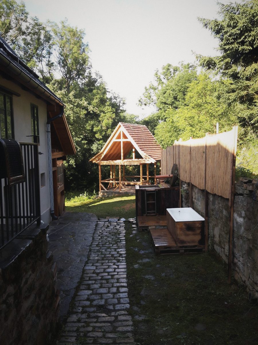 Dlážděná cesta podél domu k dřevěnému altánu